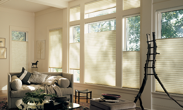 A room with a couch and some room decors with windows covered with blinds.